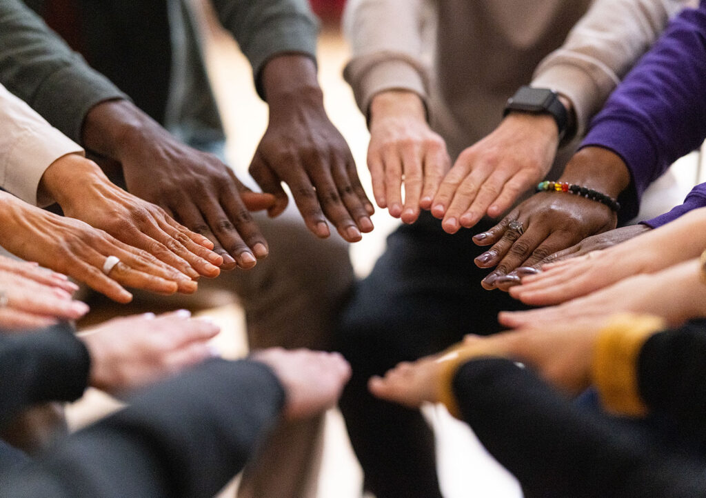 Diverse Group Of People With Their Hands Touching In A Circle.