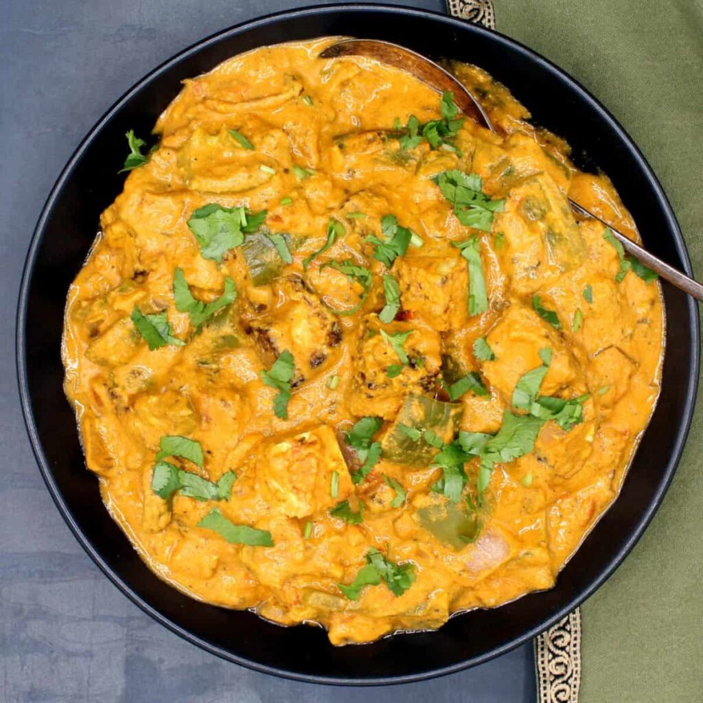 Tofu Tikka Masala In Black Bowl With Cilantro Garnish.